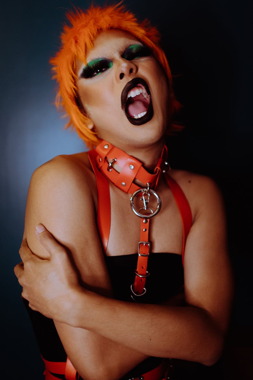 aggressive young ethnic transgender man with opened mouth in bdsm costume