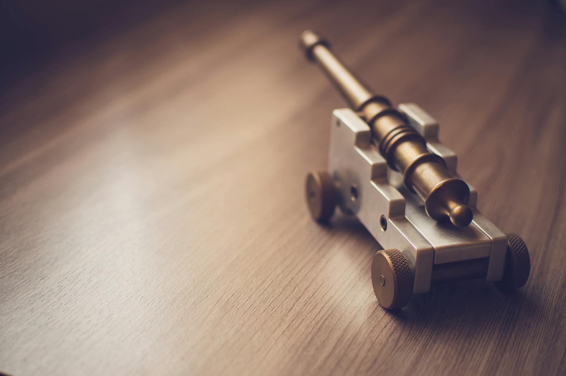 grey toy cannon on a beige wooden surface