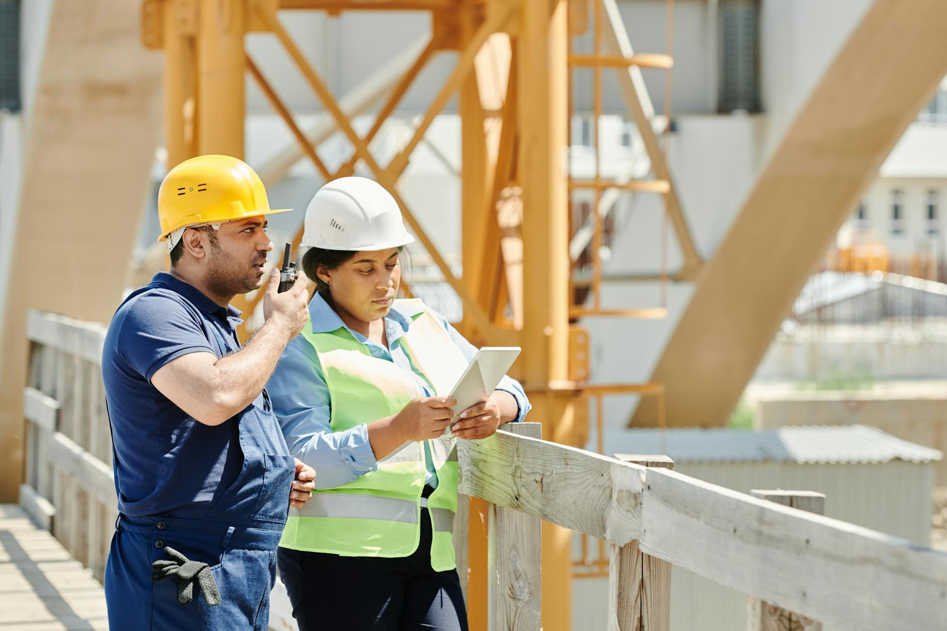 a man in blue shirt using a walkie talkie while standing beside the woman near the wooden fence