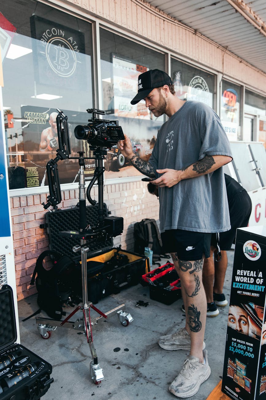 a man with tattoos standing next to a camera