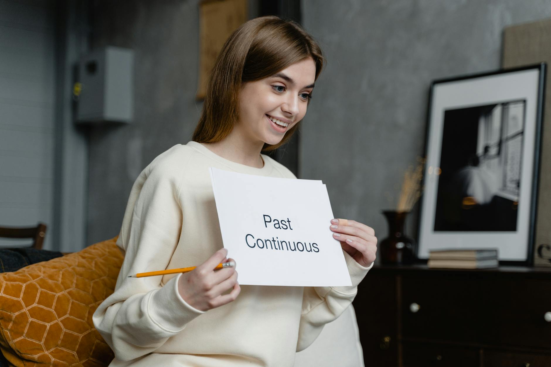smiling woman in yellow sweater holding a paper