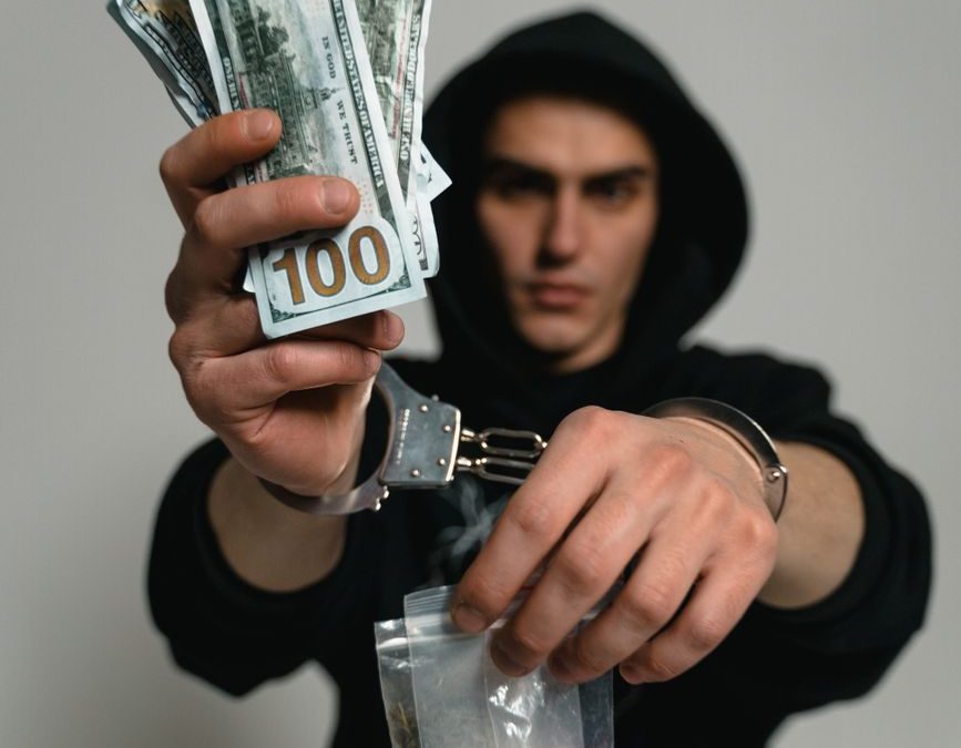 a man in handcuffs arrested for illegal drugs trade