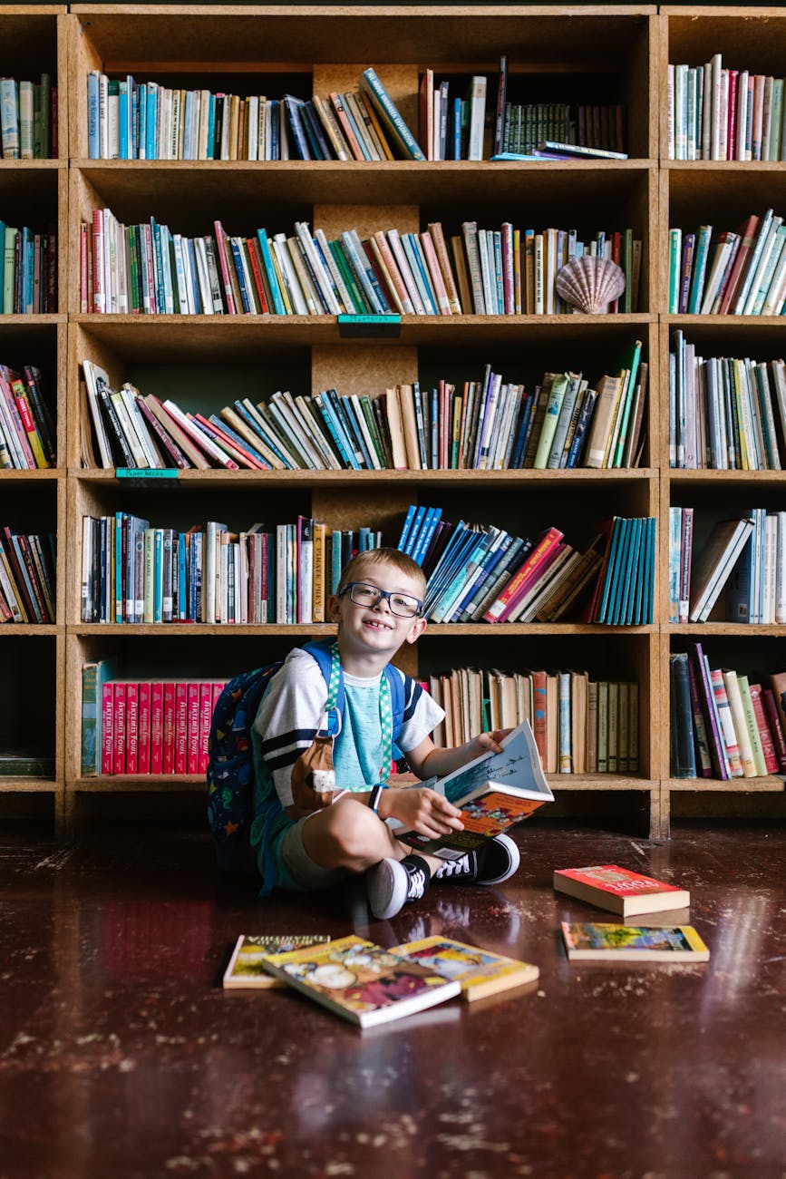 boy sitting on the floor beside the wooden book shelves
