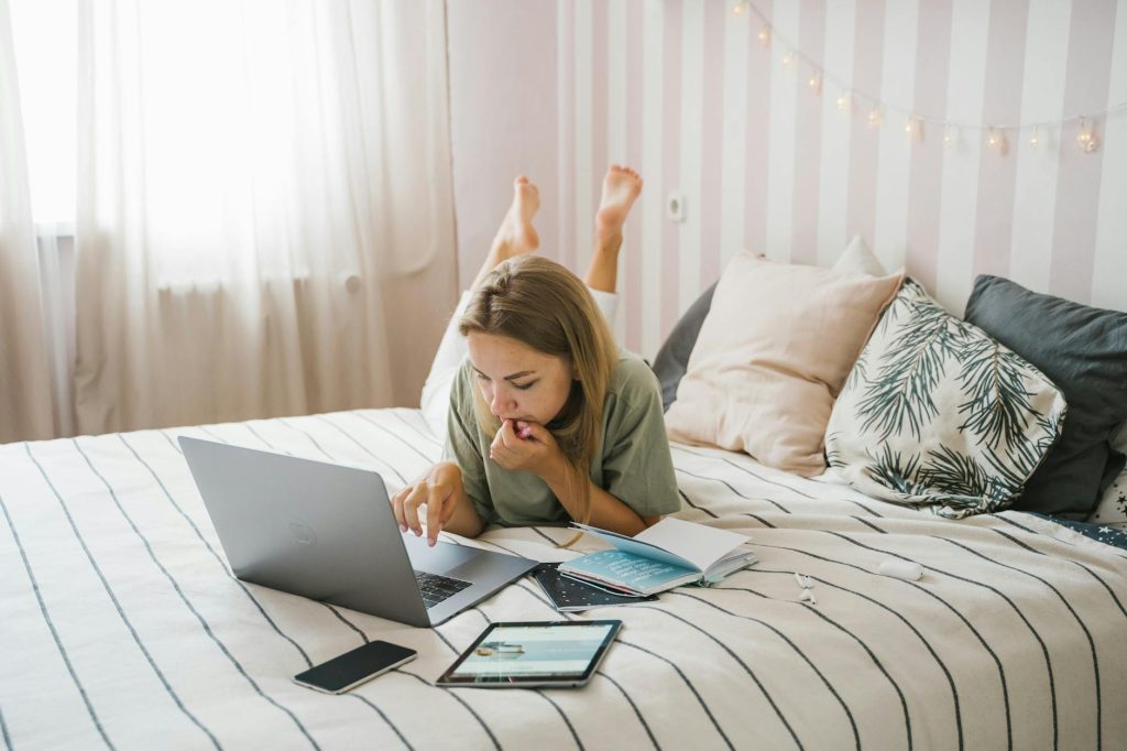 Current image: woman lying on bed while using a laptop