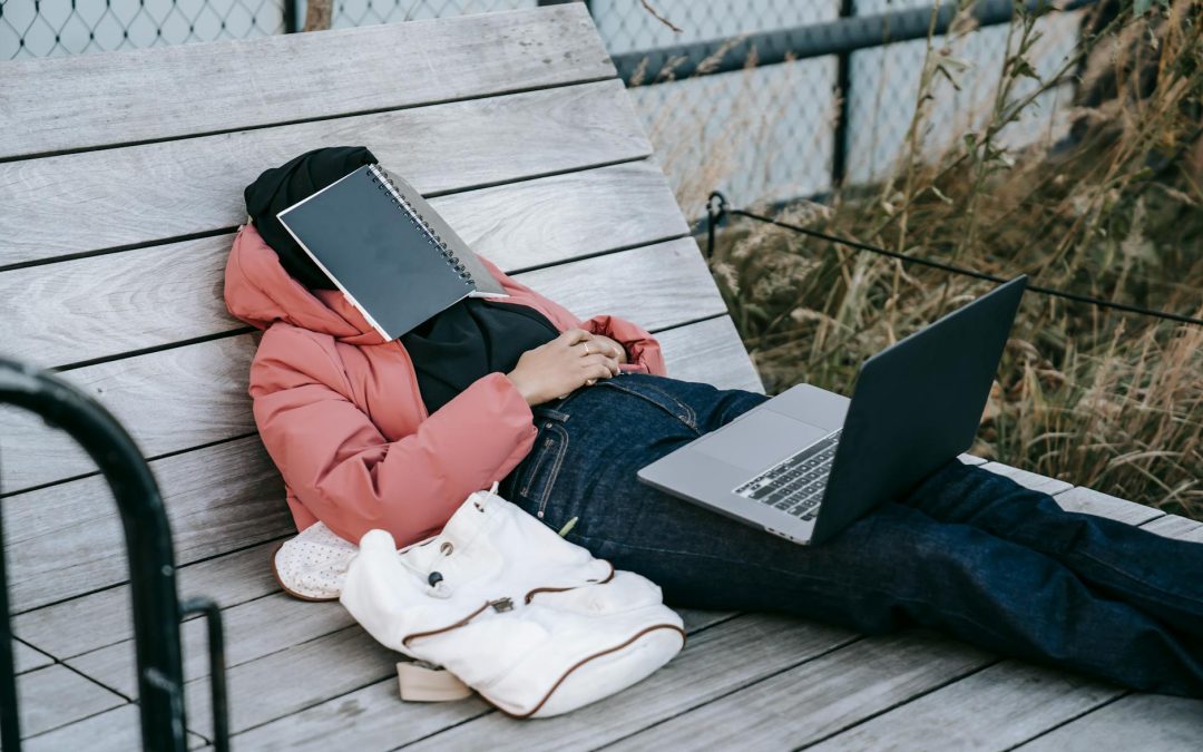 unrecognizable woman with laptop resting on bench in park