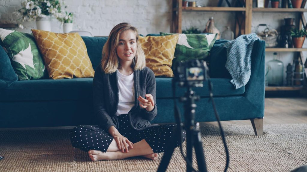 Current image: young woman vlogging at home on sofa setup