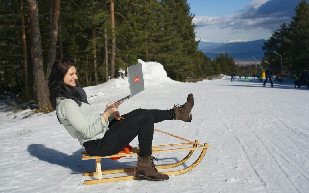 woman sitting on wooden sled using silver macbook
