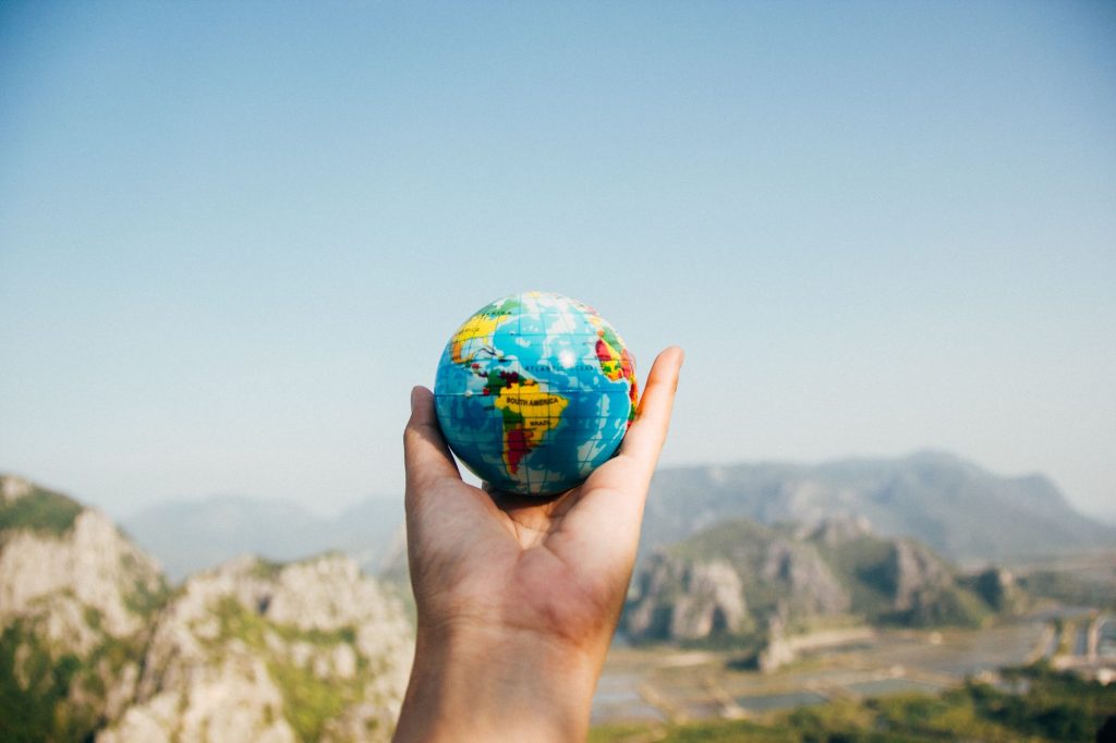 Current image: person holding world globe facing mountain