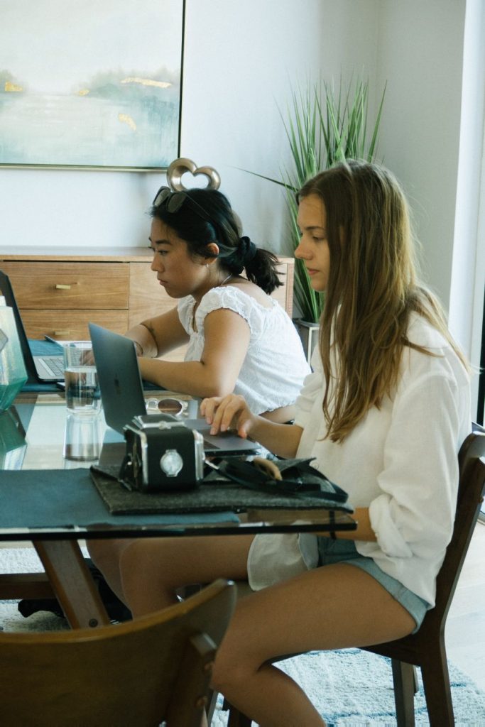 Current image: women wearing white tops sitting beside table